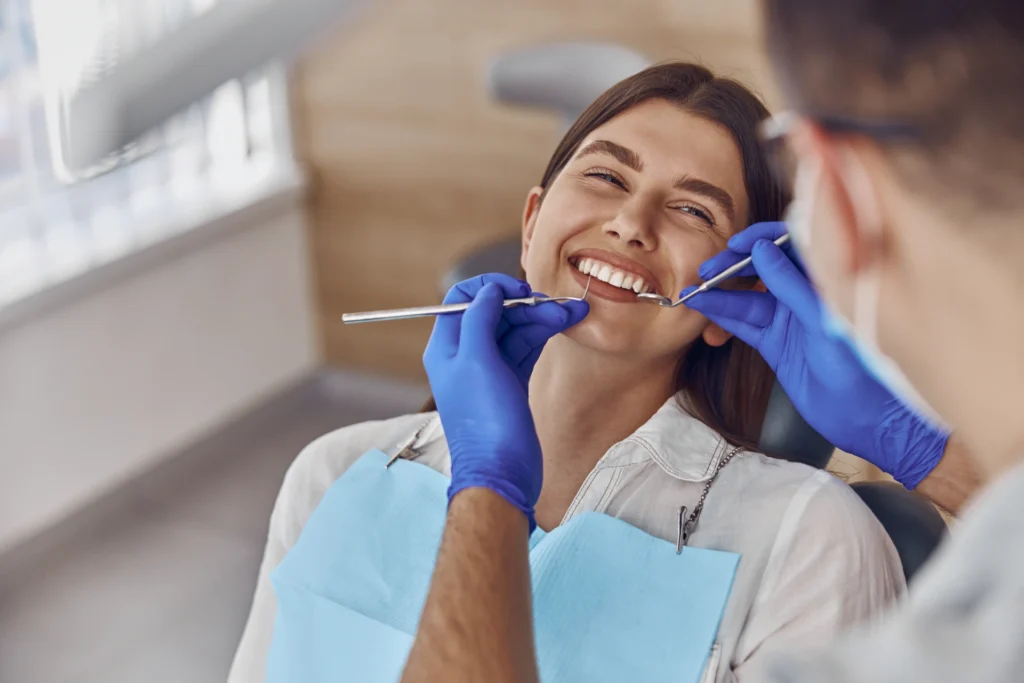 Professional doctor is checking woman's teeth in light modern dental clinic