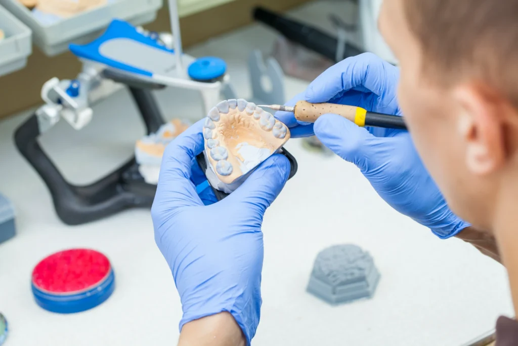 Dental technician dentist man working with dentures in a laboratory with wax on a jaw model